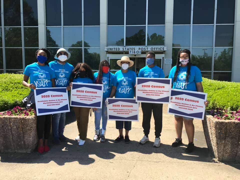 Group of young people with census signs in front of post office