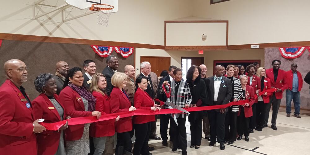 People cutting red ribbon for grand opening inside of gym